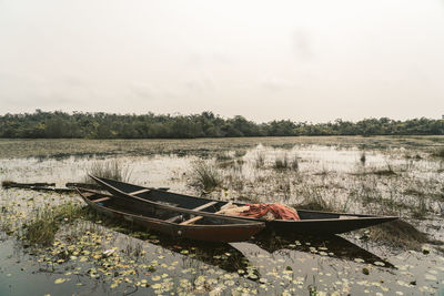 Fishing boat moored in lake against sky