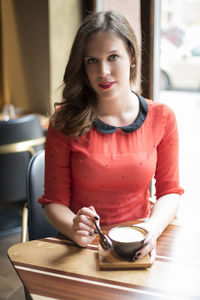 Portrait of beautiful young woman having coffee at cafe