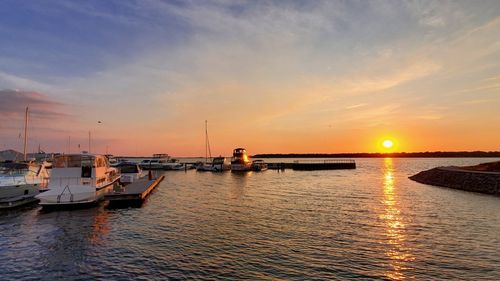 Sailboats moored in marina at sunset