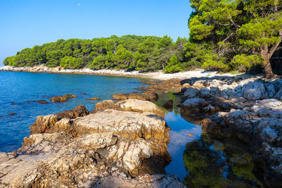 Scenic view of rocks by sea against sky