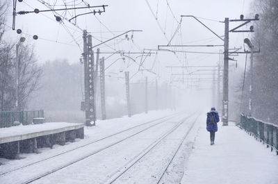 Rear view of woman walking on railroad station platform during winter