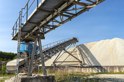 A system of interconnected conveyor belts over heaps of gravel  an industrial cement plant.
