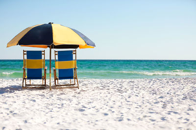 Colorful beach chairs and a beach umbrella sitting on the white sandy beach in florida