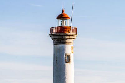 Low angle view of lighthouse by building against sky