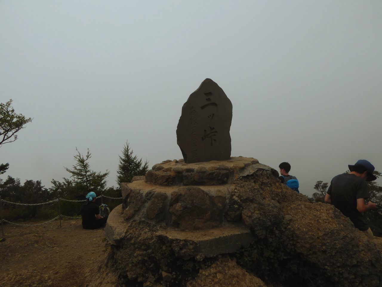 REAR VIEW OF PEOPLE ON ROCK AGAINST CLEAR SKY