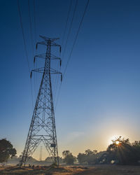 Electric pole and electric cable on the field in the countryside with blue sky.