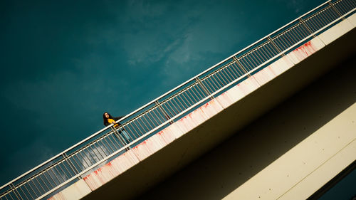 Low angle view of teenage girl on bridge against sky