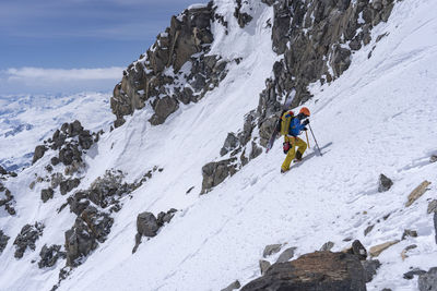 Full length of man climbing snow capped mountain