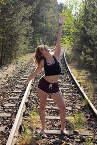 Full length of young woman standing on railroad track