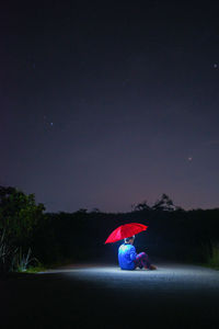 Man against illuminated blue sky at night