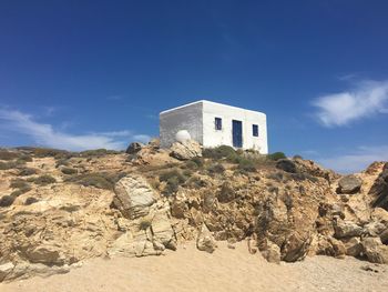 Low angle view of built structure on hill against blue sky during sunny day