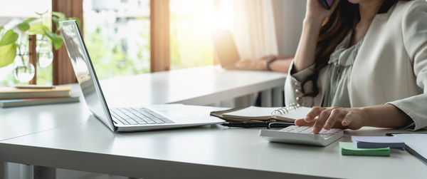 Midsection of woman using laptop on table