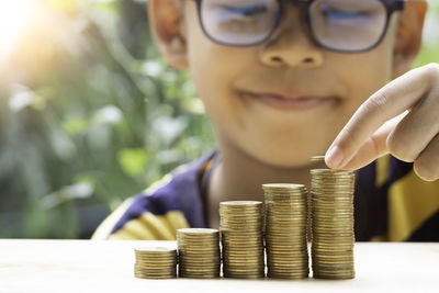 Close-up of boy stacking coins on table