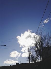 Low angle view of power lines against blue sky