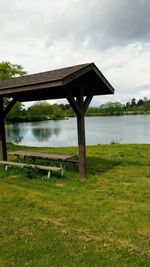 Gazebo on field by lake against sky