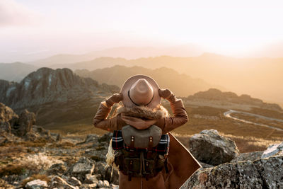 Rear view of man standing on rock against sky