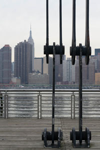 Metal structure at riverbank against empire state building in city