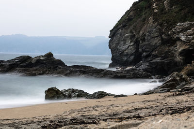 Scenic view of sea by cliff against clear sky