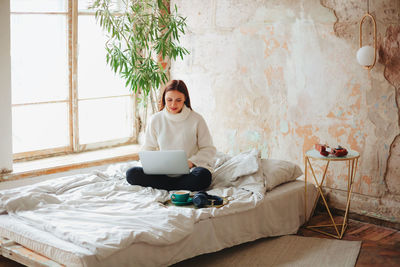 Young woman using phone while sitting at home