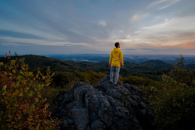 Rear view of man standing on rock against sky