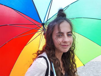 Portrait of smiling girl carrying umbrella while standing outdoors during rainy season