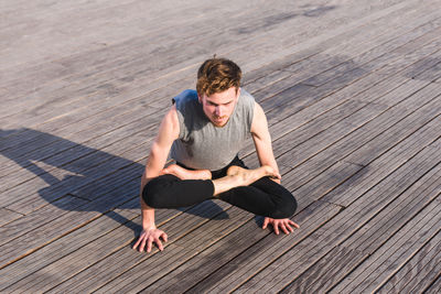 Full length of young man relaxing on wood