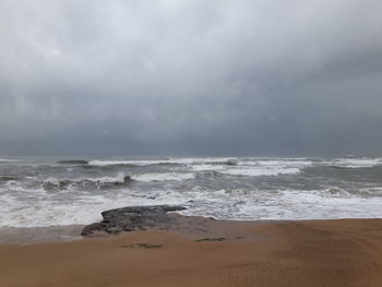 Scenic view of beach against cloudy sky