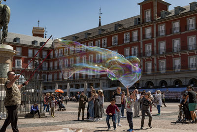 People in front of rainbow over city