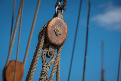 Close-up of rope tied to bollard against blue sky