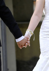 Midsection of couple holding hands during wedding ceremony