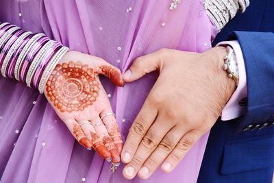 Midsection of bride showing henna tattoo with groom