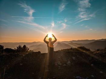 Silhouette person standing on mountain against sky during sunset