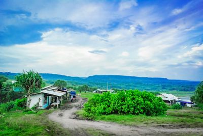 House on field by houses against sky