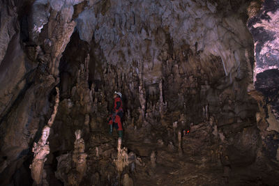 Rear view of people standing on rock in cave