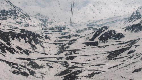Scenic view of snow covered mountains seen through glass