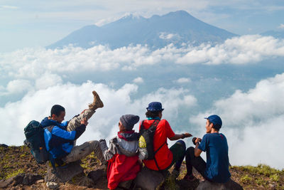 People sitting on mountain against sky