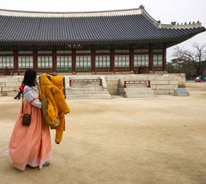 Rear view of woman outside temple against building