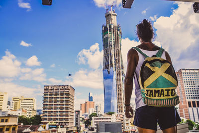 Rear view of man standing against buildings in city