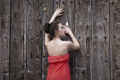 Young woman standing against wooden wall