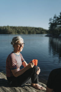 Senior woman sitting on rock at lakeshore