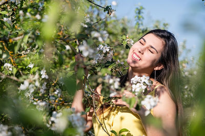 Portrait of smiling young woman standing against trees