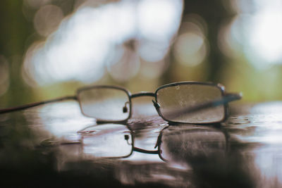 Close-up of eyeglasses on wet table during sunny day