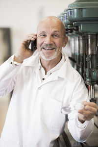 Portrait of smiling engineer answering mobile phone in factory