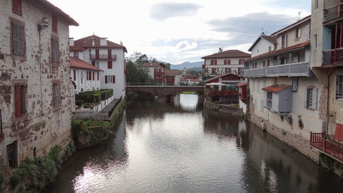 Canal amidst houses and buildings against sky