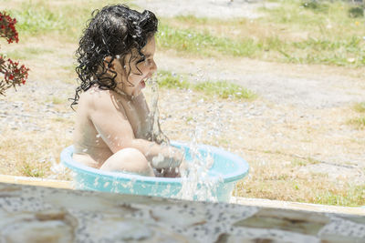 Happy girl playing in bucket with water