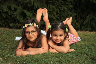 Portrait of sisters lying down on grassy land