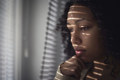 Pensive young woman looking through window