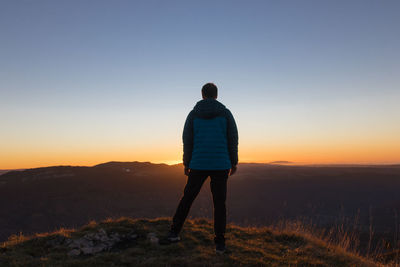 Man above the cliff of moutier-haute-pierre facing the setting sun