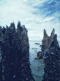 Rock formations on sea against cloudy sky