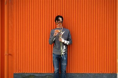 Portrait of boy standing against orange wall